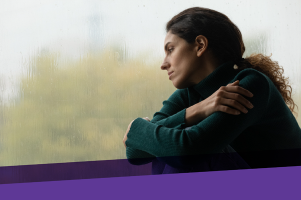 young woman looking out a window on a gloomy day