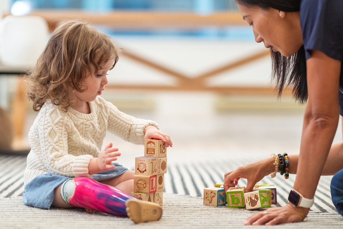 young girl playing with blocks on floor with pediatric therapist